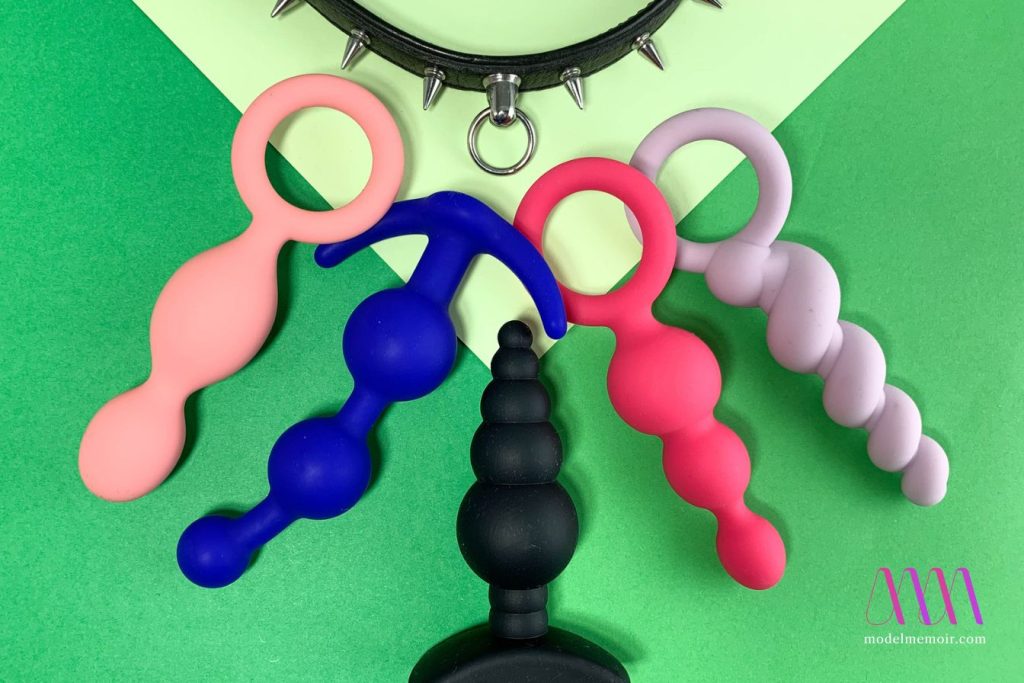 Five butt plugs and collar on a green background.