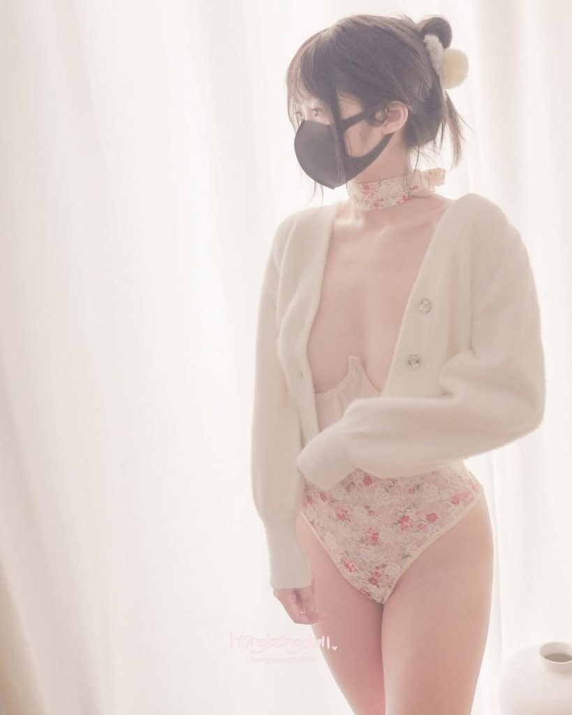 HongKongDoll in delicate pink lingerie and a light cardigan, posing elegantly.