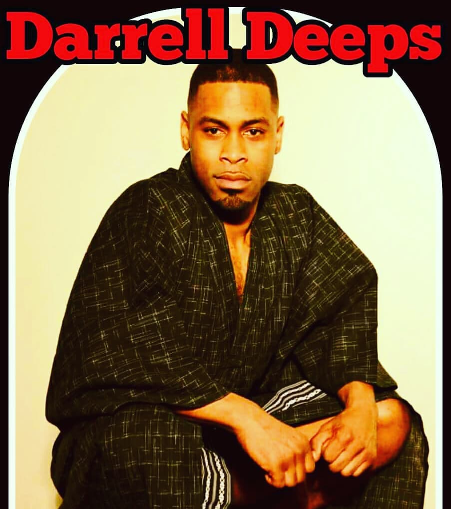 Darrel Deeps wearing a luxurious robe, posing confidently.