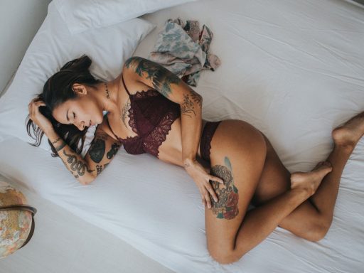 Sexy tattoed pornstar woman lying on bed.