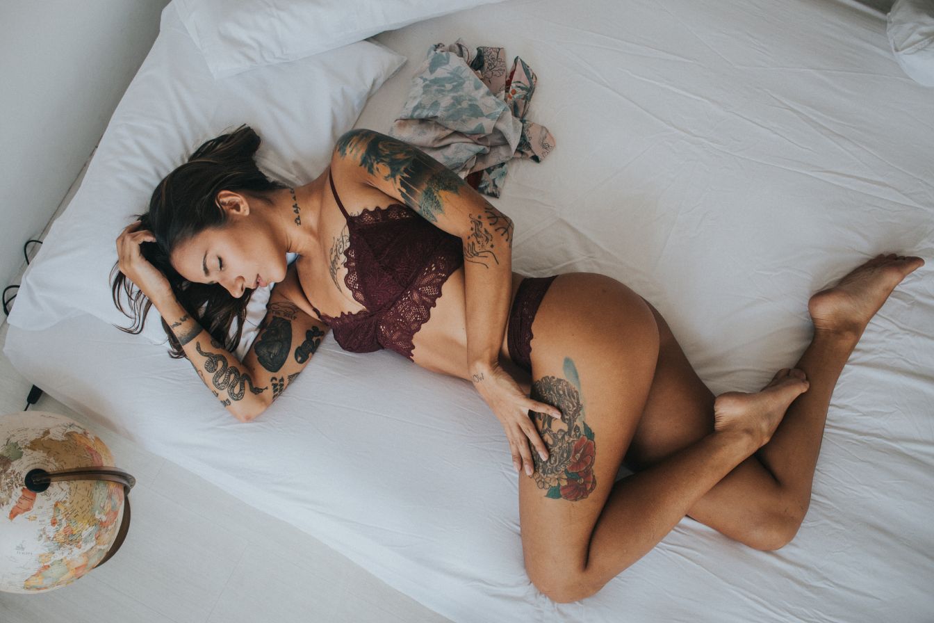 Sexy tattoed pornstar woman lying on bed.